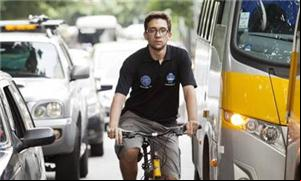 Philipe Moura pedala entre ônibus e carros na rua